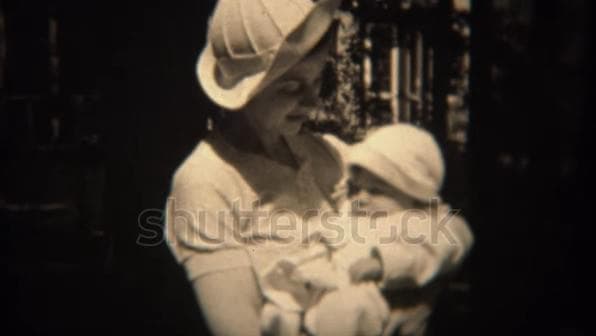 1930s footage mother holding newborn baby in formal outdoor clothing.